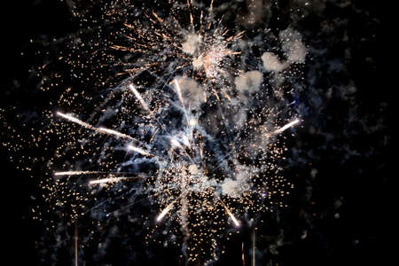 A shining colorful firework is over a dark night skyの写真素材