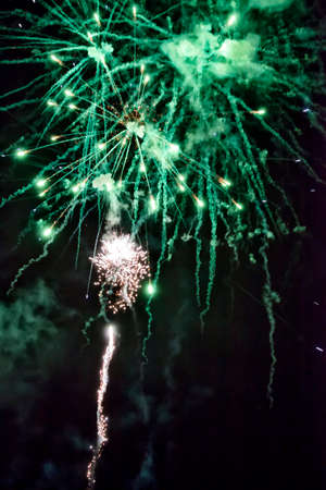 A shining colorful firework is over a dark night skyの写真素材