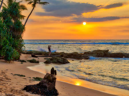 A gorgeous sundown with warm and luminous colors in gold, orange, red, over the wild Indian Ocean in Asia on the fascinating tropical island Sri Lankaの写真素材