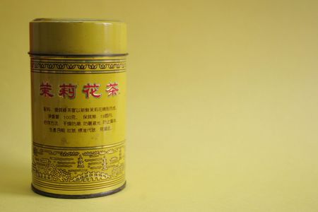 Old Chinese tea tin on yellow background - copy spaceの写真素材