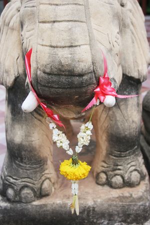 Flowers hanging on an elephant statue in Thailandの写真素材