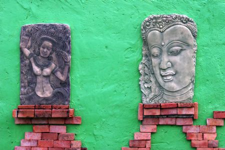 Thai-style statues on a green wallの写真素材
