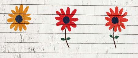 Three colorful flowers painted on a wooden wallの写真素材