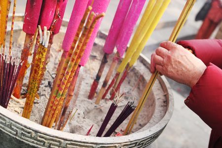 Close-up of an old woman's hands as she offers incense at a temple in China - travel and tourism.の写真素材