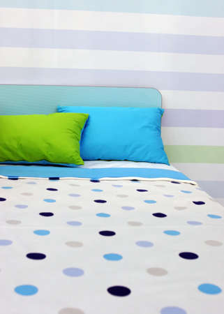 Bed with bright blue and green linen - home interiors
