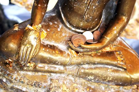 Close-up of a Buddhist statue holding offerings of money in Thailand - travel and tourismの写真素材