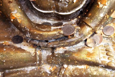 Close-up of a gold Buddhist statue holding offerings of coins in Thailand - travel and tourismの写真素材