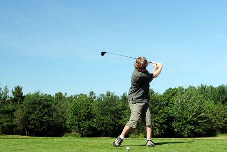 Man tees off at the golf course.の写真素材