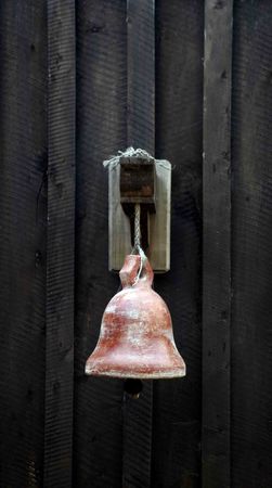 Old metal bell hanging on a black wall.の写真素材