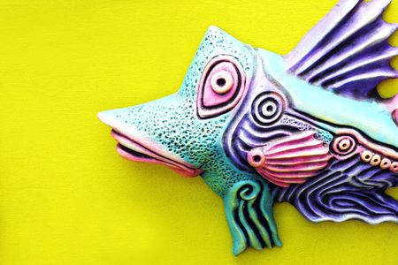 Bright ceramic fish on a yellow background.の写真素材
