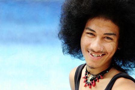 Portrait of a young Thai man with an afro isolated on blue.