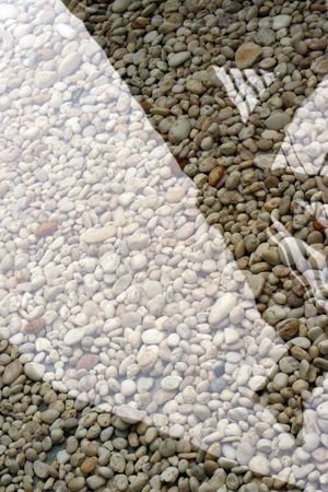 Brown stones in water with a reflection.の写真素材