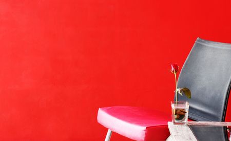Red rose on a table next to a chair.の写真素材