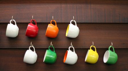 Colorful coffee cups hanging on a wall.の写真素材