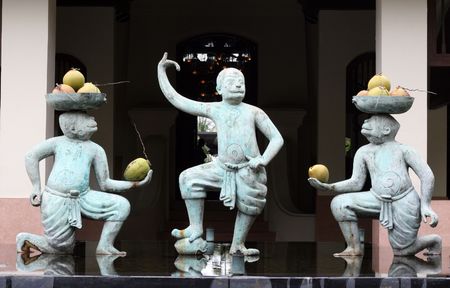 Monkey statues holding fruit in a water garden.の写真素材