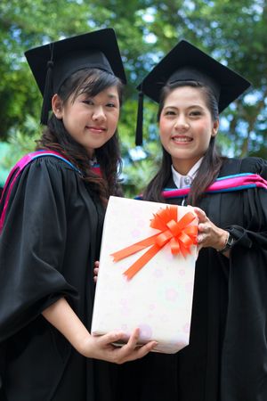 Asian university graduates with a gift (focus on the gift).
