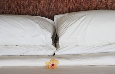 Close-up of a bed with white linen and a flower.の写真素材