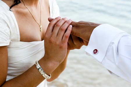 Close-up of a bride slipping the ring onto the groom's finger.