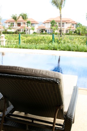 Swimming pool with deck chairs overlooking a lush garden.の写真素材