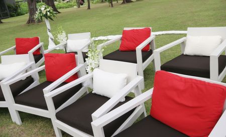 Seating arrangement decorated with flowers at a wedding ceremony outdoors.