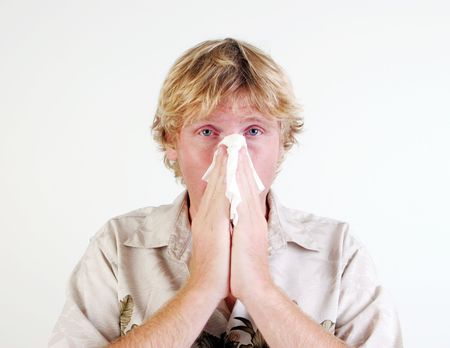 Young man with a cold or flu sneezing - isolated.の写真素材