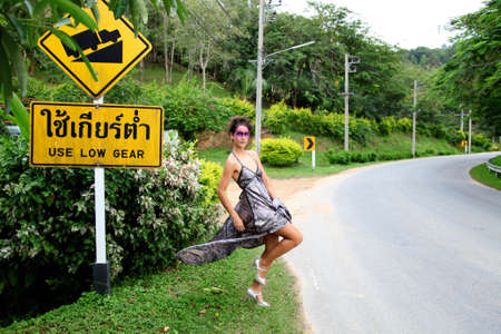 Woman in evening wear on the road hitchhiking.の写真素材