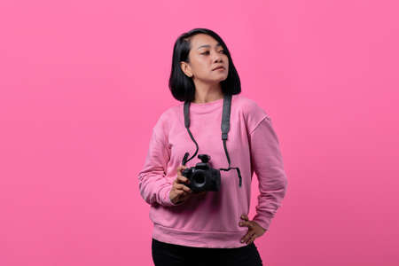 Young woman holding camera with flat expression