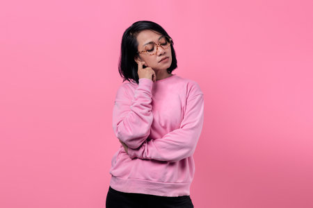 Portrait of Asian girl wearing pink jacket looking pensive, sad and unhappyの写真素材