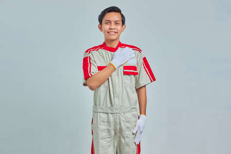 Portrait of young mechanic man greeting with big smile on his face isolated on gray backgroundの写真素材