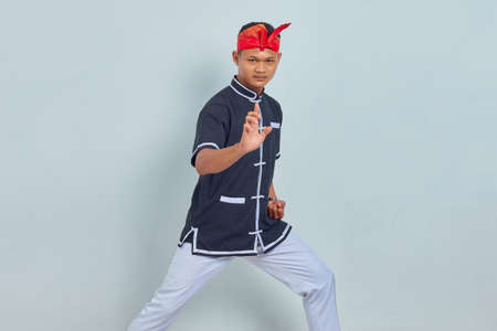 Picture of young sportsman dressed in kimono practice in karate isolated over grey background....
