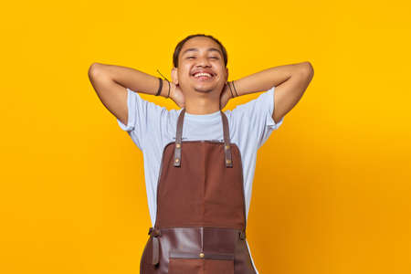 Portrait of calm and relaxed Asian young man relieving stress, closing his eyes and smiling peacefully isolated on yellow backgroundの写真素材
