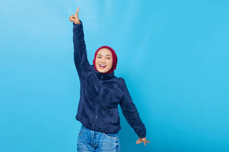 Portrait of beautiful young Asian woman dancing happy and cheerful on blue background