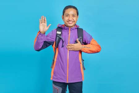 Portrait of smiling handsome man with hands on chest and open palms on blue background
