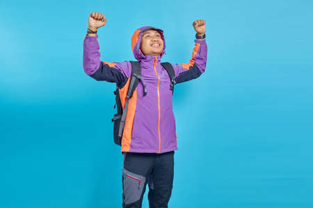 Portrait of cheerful handsome Asian man rejoicing celebrating luck on blue backgroundの写真素材