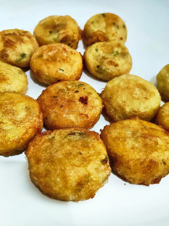 Fried potato balls on a white plate. Close-up.