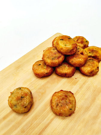 Fried fish cakes on a wooden board on a white background.