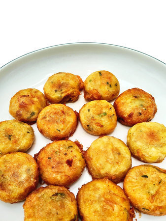 Fried potato balls on a plate, isolated on white background.