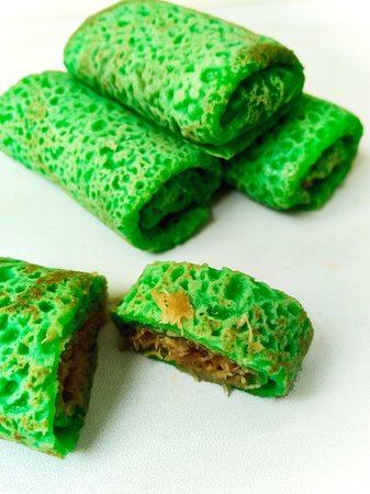 Several pieces of traditional Indonesian Dadar Gulung, a sweet green rolled pancake filled with...