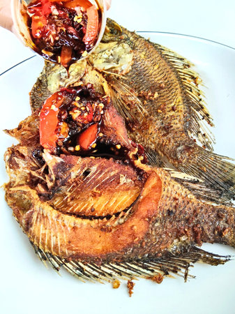 Deep fried tilapia fish with chili sauce on white plate.の写真素材