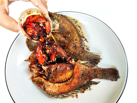 Fried tilapia fish with sweet chili sauce on white backgroundの写真素材