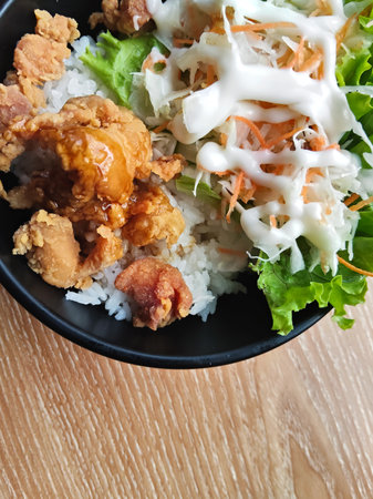 Rice topped with fried chicken and salad on wooden table, stock photoの写真素材