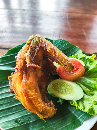 Fried chicken wings on banana leaf with vegetable on wooden background.の写真素材