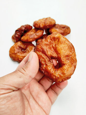 A person's hand holds a delicious and traditional sweet Sundanese cake, with a bite revealing its...