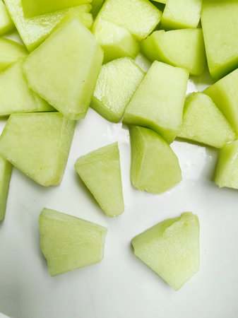 Green melon slices on a white plate. Close-up.