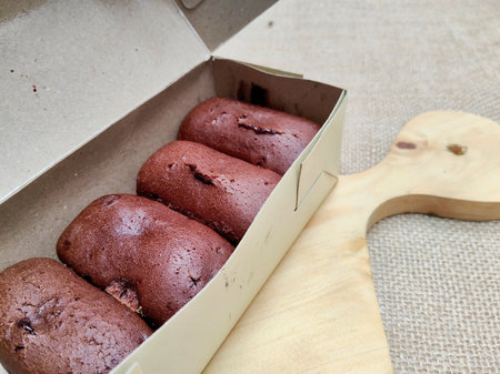 Chocolate muffins in a paper box on a wooden table.の写真素材
