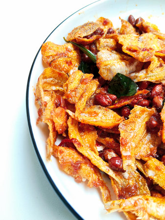 Fried dish with chili sauce in white dish on white background.