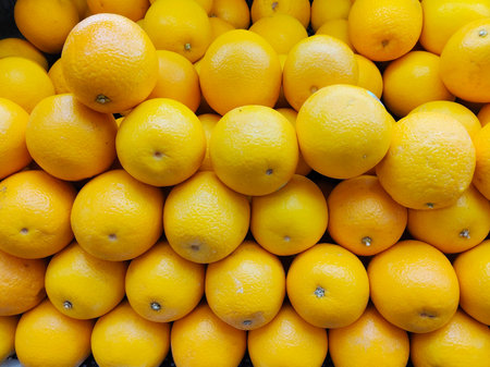 Large Stack of Bright Yellow Orange Citrus Fruits Piled Up for Sale in a Marketの写真素材