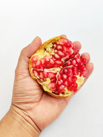Pomegranate fruit in hand isolated on a white background.の写真素材