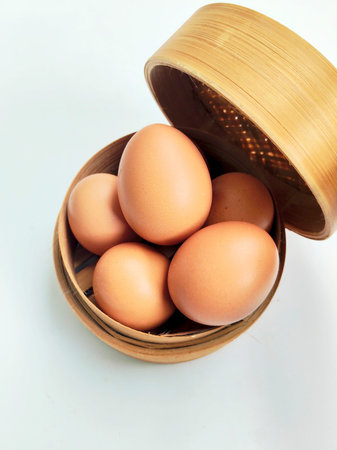 Eggs in bamboo basket on white background, top view.の写真素材