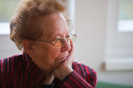 An old woman sits thoughtfully at the window
